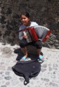 A little girl plays the accordion for tips